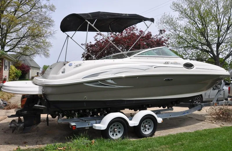 Slide: The Image of 2006 Sea Ray 240 Sundeck boat on trailer, parked outdoors with trees in background. - 4