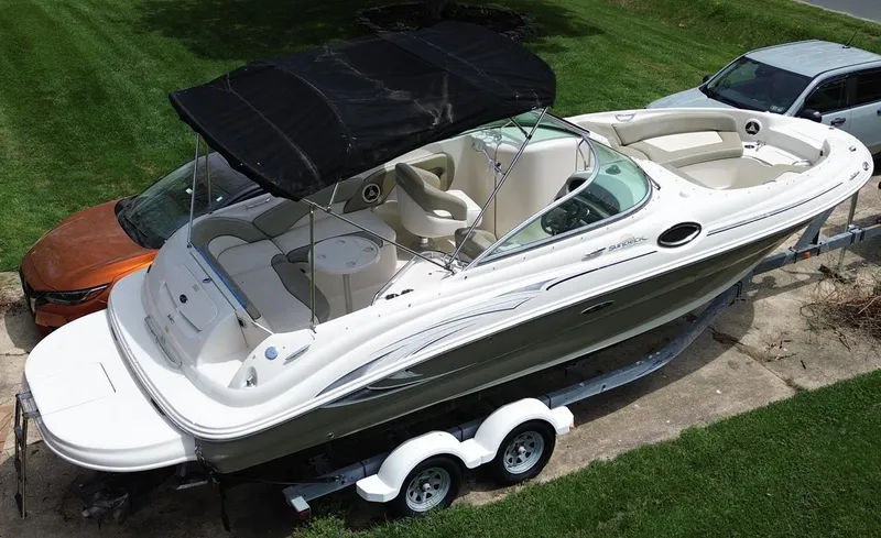 Slide: The Image of 2006 Sea Ray 240 Sundeck boat on trailer, parked on grass, with black canopy. - 7