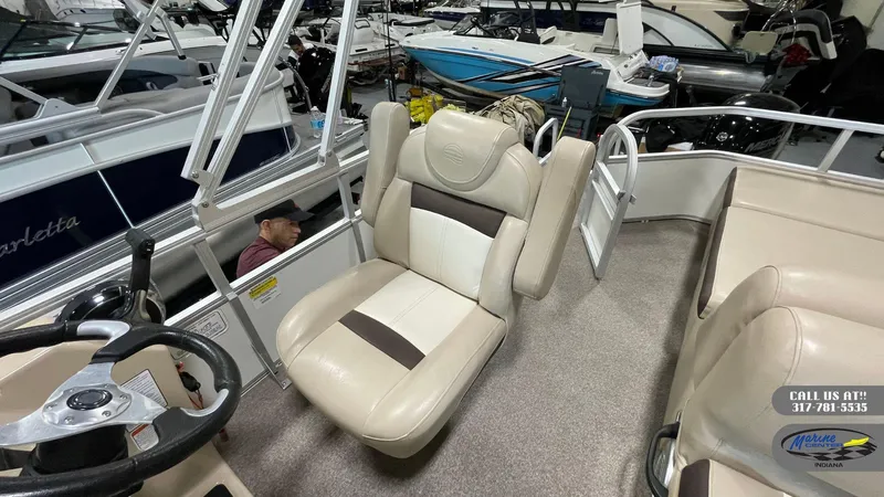 Slide: The Image of 2016 Sun Tracker Party Barge 22 DLX interior with beige seating and steering wheel. - 3