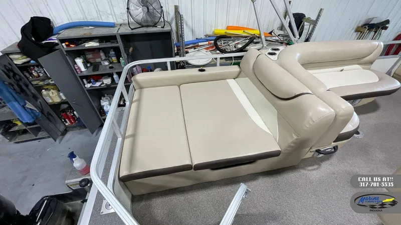 Slide: The Image of 2016 Sun Tracker Party Barge 22 DLX interior with beige seating in a workshop setting. - 4