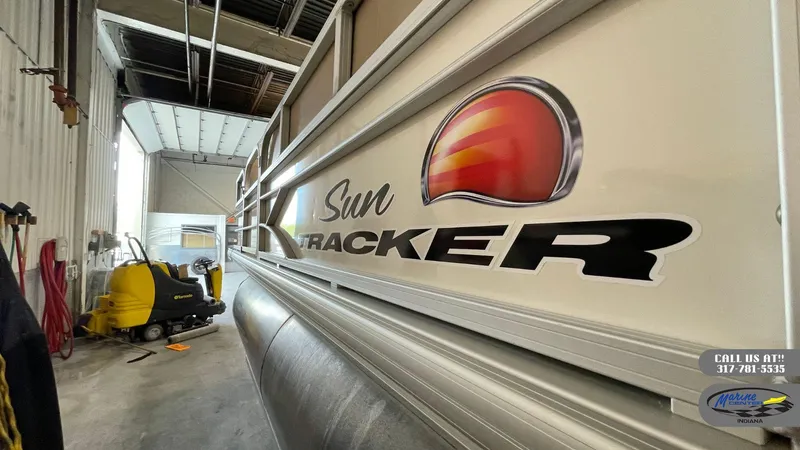 Slide: The Image of 2016 Sun Tracker Party Barge 22 DLX in storage, showcasing logo and side view. - 8