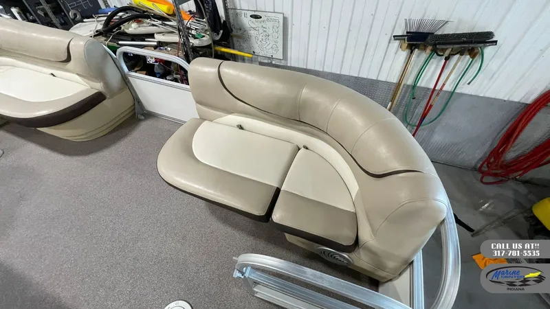 Slide: The Image of 2016 Sun Tracker Party Barge 22 DLX interior seating with beige upholstery in a showroom. - 9