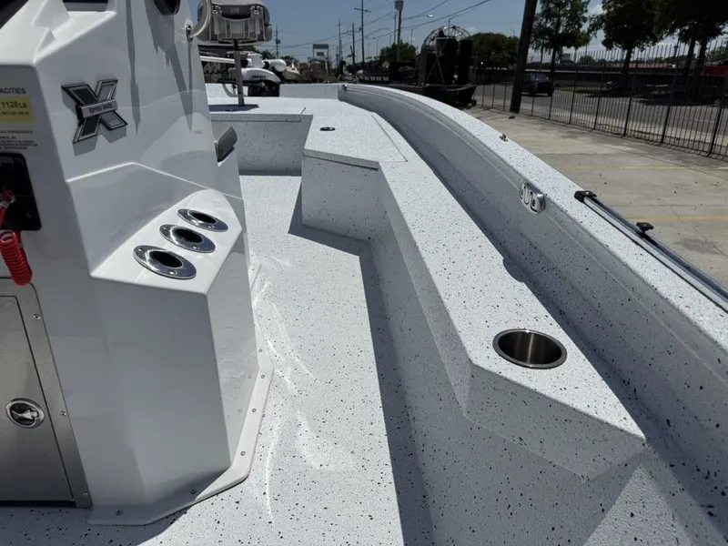 Slide: The Image of 2023 Xpress H22 Bay boat interior with rod holders and cup holder, parked outdoors. - 11