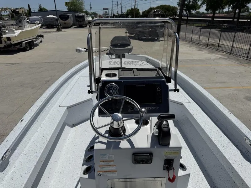 Slide: The Image of 2023 Xpress H22 Bay boat dashboard with steering wheel and controls in a marina setting. - 16