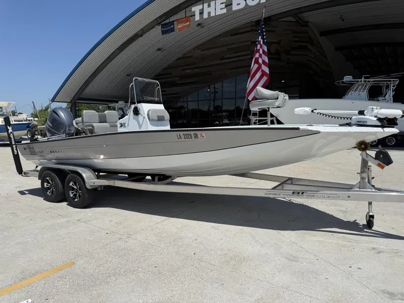 Slide: The Image of 2023 Xpress H22 Bay boat on trailer, parked outside dealership with American flag. - 19