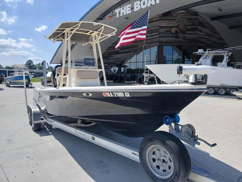 Slide: The Image of 2013 BlackJack 224 boat on trailer, parked outside dealership with American flag. - 12