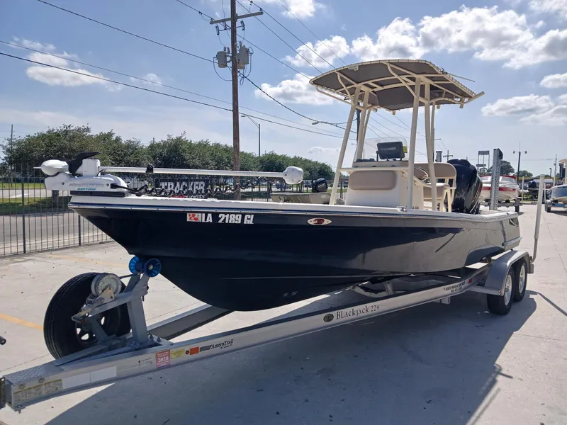 Slide: The Image of 2013 BlackJack 224 boat on trailer, parked outdoors under a clear sky. - 6