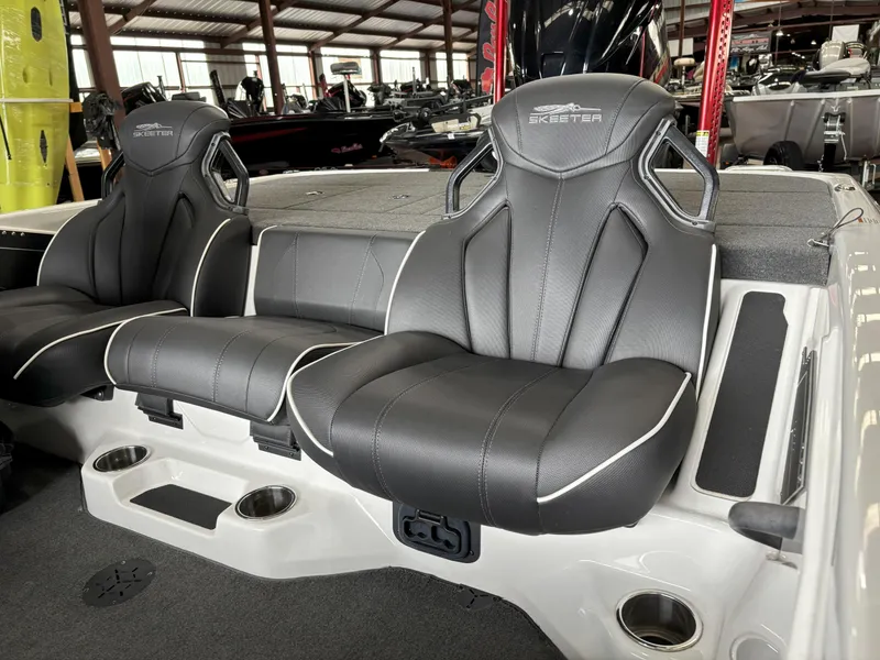 Slide: The Image of 2021 Skeeter ZXR21 boat seats in showroom, featuring sleek black design and cup holders. - 8