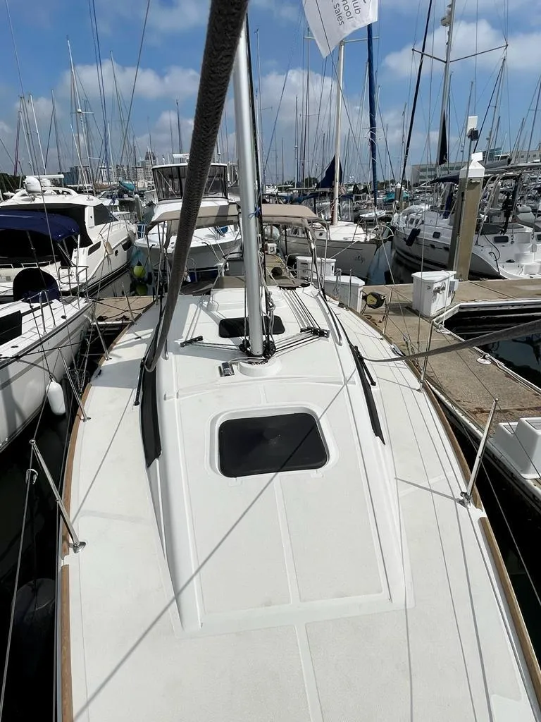 Slide: The Image of 2021 Jeanneau Sun Odyssey 319 sailboat docked in a marina, surrounded by other boats. - 2