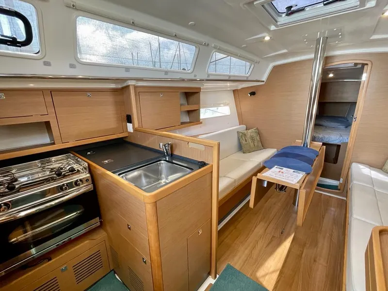 Slide: The Image of Interior of 2021 Jeanneau Sun Odyssey 319 sailboat with modern kitchen and cozy seating area. - 6
