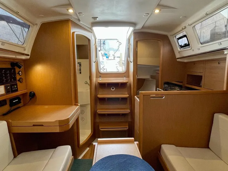 Slide: The Image of Interior of 2021 Jeanneau Sun Odyssey 319 sailboat, featuring cozy seating and wooden cabinetry. - 7