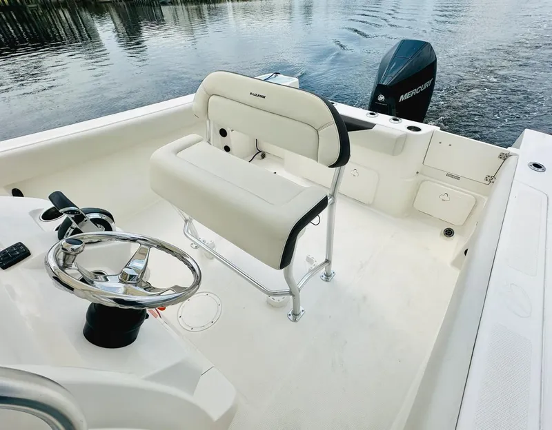 Slide: The Image of 2022 Sailfish 242 CC boat interior with steering wheel and seating, docked by water. - 12