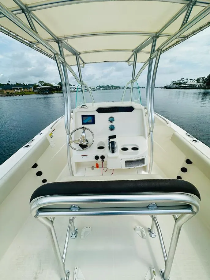 Slide: The Image of 2022 Sailfish 242 CC boat interior with steering console and seating, on calm water. - 13
