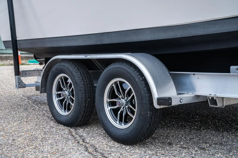 Slide: The Image of Trailer wheels of 2022 Sailfish 242 CC boat on pavement. - 21
