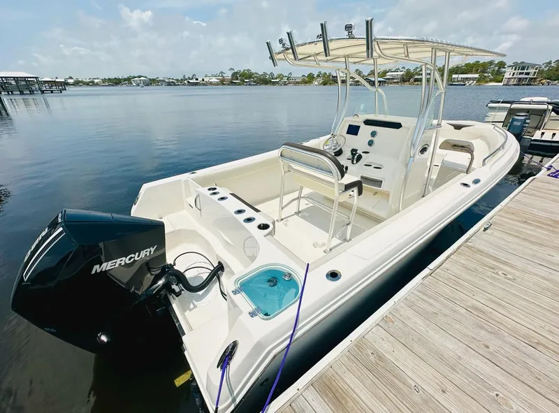 Slide: The Image of 2022 Sailfish 242 CC boat docked, featuring a Mercury outboard motor, on a sunny day. - 8