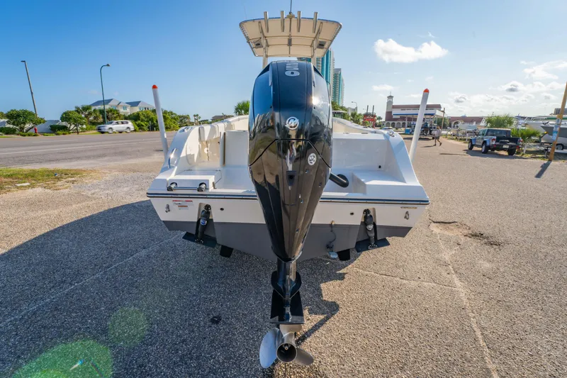 Slide: The Image of 2022 Cobia 237 CC boat on trailer, parked near tall buildings under a clear blue sky. - 2