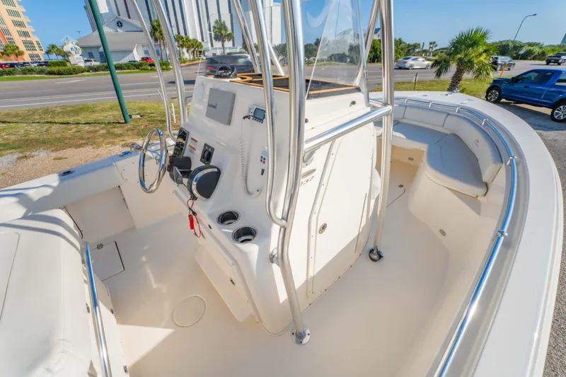 Slide: The Image of 2022 Cobia 237 CC boat interior with steering console and seating, parked near a road. - 21