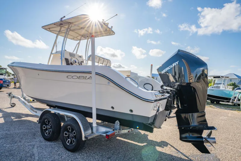Slide: The Image of 2022 Cobia 237 CC boat on trailer with Mercury engine, parked near buildings. - 3