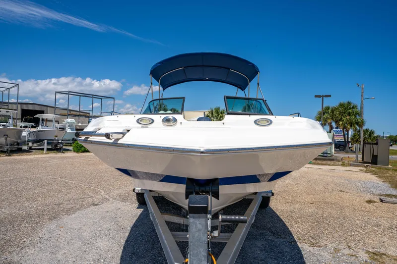 Slide: The Image of 2020 NauticStar 203 DC boat on trailer, blue canopy, parked outdoors under clear sky. - 13