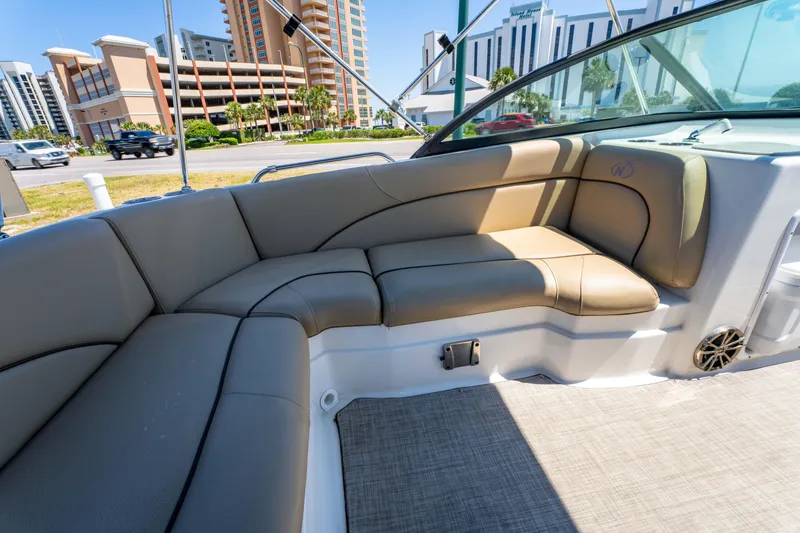 Slide: The Image of 2020 NauticStar 203 DC boat interior with beige seating and cityscape background. - 15