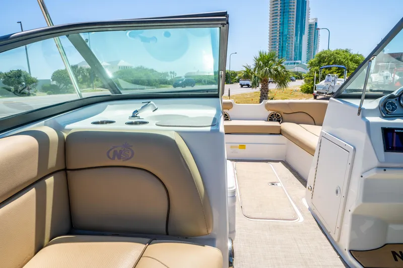 Slide: The Image of 2020 NauticStar 203 DC boat interior with beige seating and cityscape background. - 17