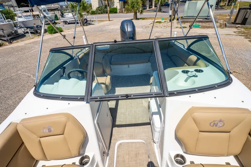 Slide: The Image of 2020 NauticStar 203 DC boat interior with tan seating and windshield view. - 19