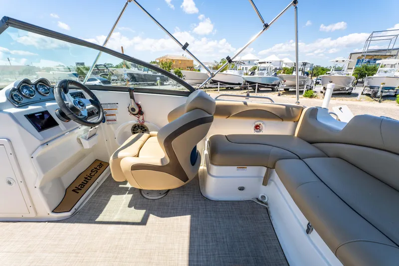 Slide: The Image of 2020 NauticStar 203 DC boat interior with beige seating and modern dashboard. - 8