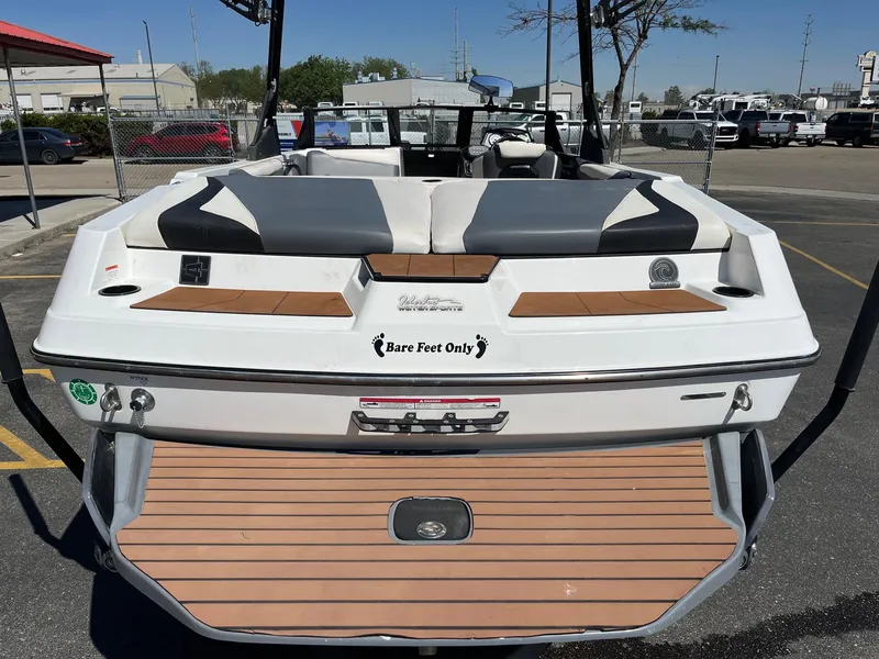 Slide: The Image of 2021 Axis T22 boat rear view with "Bare Feet Only" decal, parked in a lot. - 7