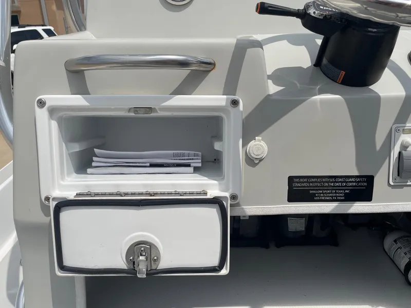 Slide: The Image of 2020 Shallow Sport 18 Sport boat console with open storage compartment and safety compliance label. - 23
