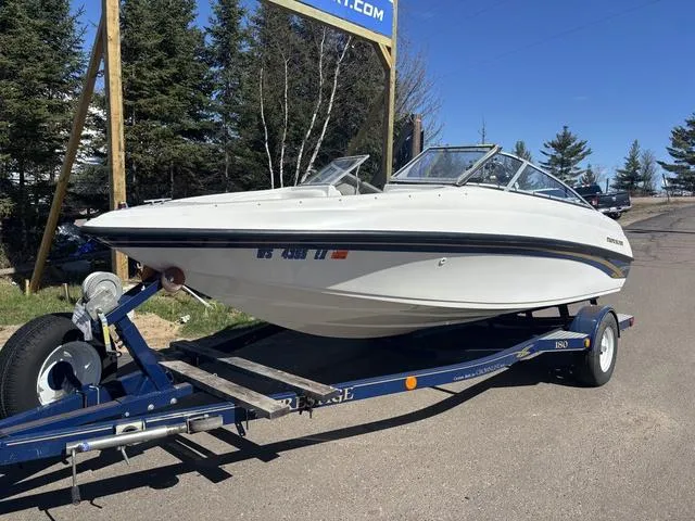 Slide: The Image of 2000 Crowline 180 BR boat on trailer, parked outdoors near trees. - 2