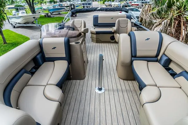 Slide: The Image of 2025 Starcraft EX20QDH boat interior with beige and navy seating, docked near greenery. - 10