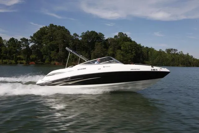 Slide: The Image of 2009 Yamaha Boats SX 230 speeding on a lake with lush green trees in the background. - 17