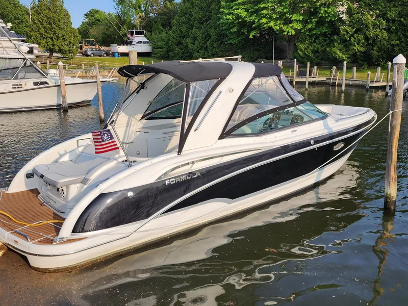 The Image of 2008 Formula 310 Bowrider boat docked in a marina, featuring sleek design and American flag. - 1