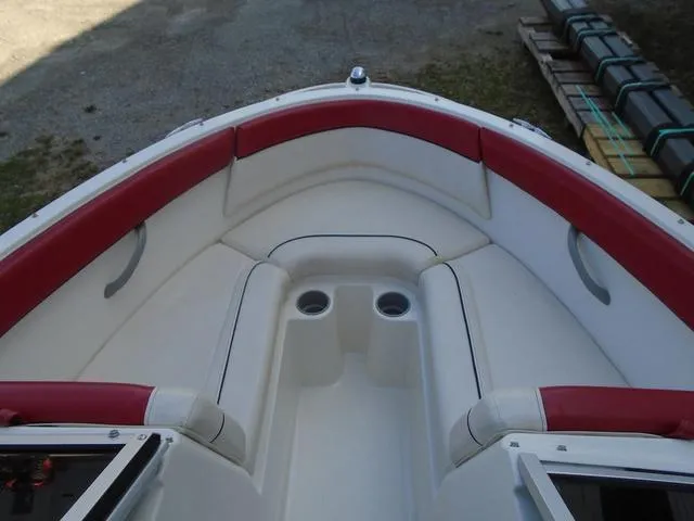 Slide: The Image of 2013 Bayliner 185 Bowrider interior with red and white seating, cup holders, and open bow design. - 14