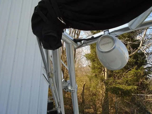 Slide: The Image of 2013 Bayliner 185 Bowrider with mounted speaker and canopy, outdoors near trees. - 20