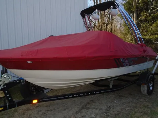Slide: The Image of 2013 Bayliner 185 Bowrider with red cover on trailer, parked outdoors. - 23