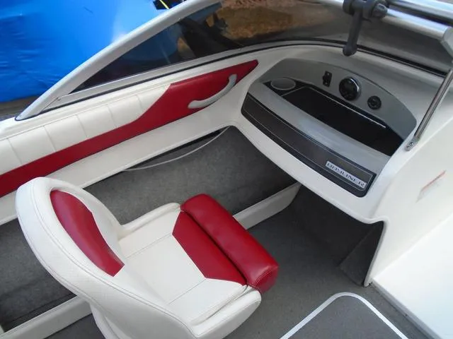 Slide: The Image of 2013 Bayliner 185 Bowrider interior with red and white seating, dashboard, and storage compartment. - 6