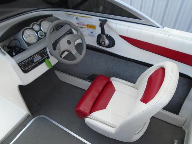 Slide: The Image of 2013 Bayliner 185 Bowrider interior with steering wheel, gauges, and red-accented seating. - 7