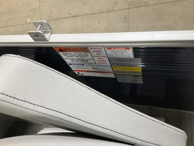 Slide: The Image of 2023 Bennington 23 SXSR boat seat with visible warning labels and latch mechanism. - 12