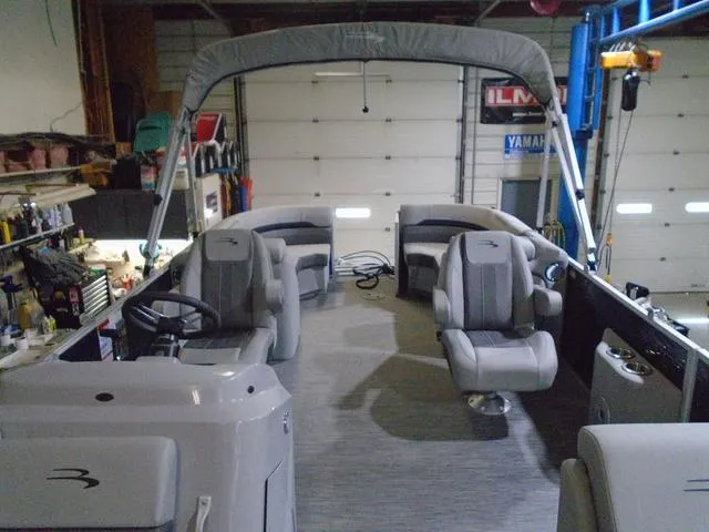 Slide: The Image of 2023 Bennington 23 SXSR pontoon boat interior with gray seating and helm in a garage setting. - 6