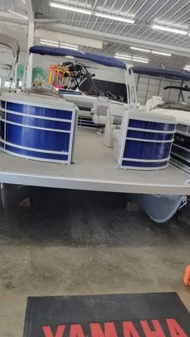Slide: The Image of 2023 Bennington 23 LSB pontoon boat in showroom, featuring blue exterior and spacious deck. - 16