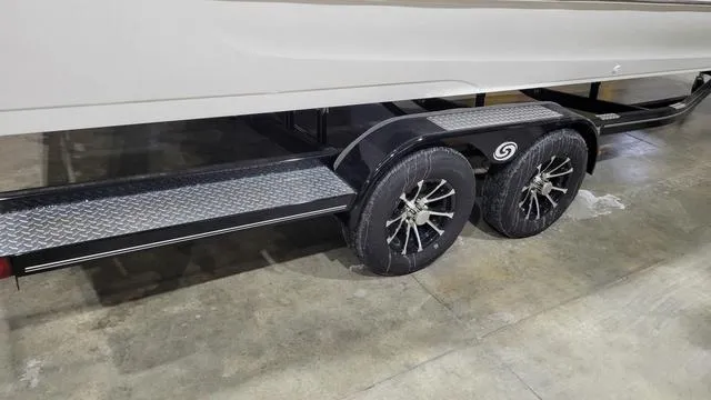 Slide: The Image of 2024 Hurricane FunDeck 2360 SBC OB trailer with dual wheels on a concrete floor. - 11
