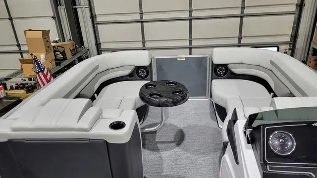 Slide: The Image of 2024 Hurricane FunDeck 2360 SBC OB interior with seating and table in a garage setting. - 3