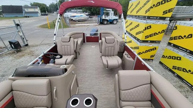 Slide: The Image of 2023 Bennington 22 SSR pontoon boat with beige seating and red canopy, docked near Sea-Doo boxes. - 1