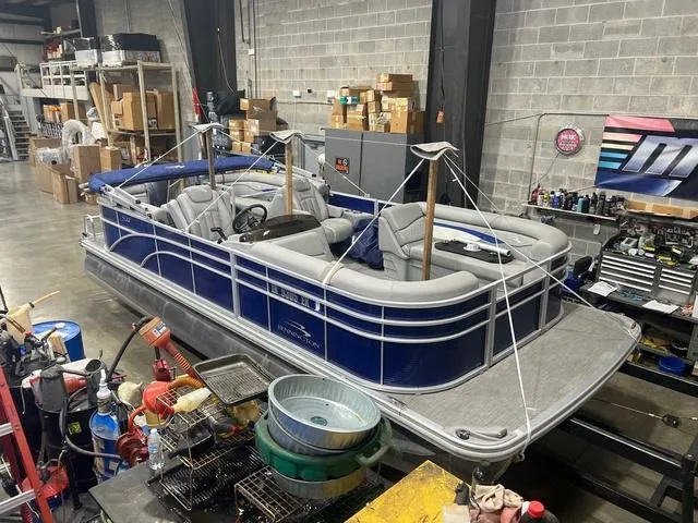 Slide: The Image of 2023 Bennington 22 SSR pontoon boat in a warehouse, surrounded by tools and equipment. - 1