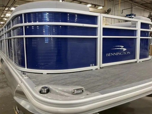 Slide: The Image of 2023 Bennington 22 SSR pontoon boat with blue paneling and sleek design in a warehouse setting. - 3