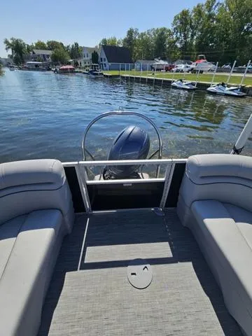 Slide: The Image of 2023 Bennington 24 SSR pontoon boat on a serene lake with scenic shoreline views. - 13