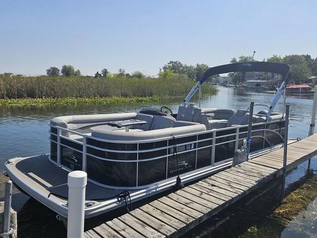 Slide: The Image of 2023 Bennington 24 SSR pontoon boat docked on a sunny day by a serene lake. - 14