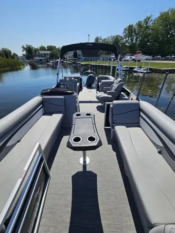 Slide: The Image of 2023 Bennington 24 SSR pontoon boat with spacious seating on a calm lake. - 2