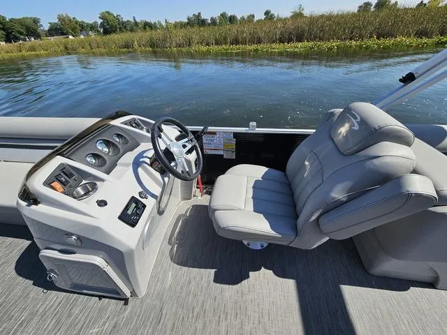 Slide: The Image of 2023 Bennington 24 SSR boat interior with steering wheel and comfortable seating by the water. - 7